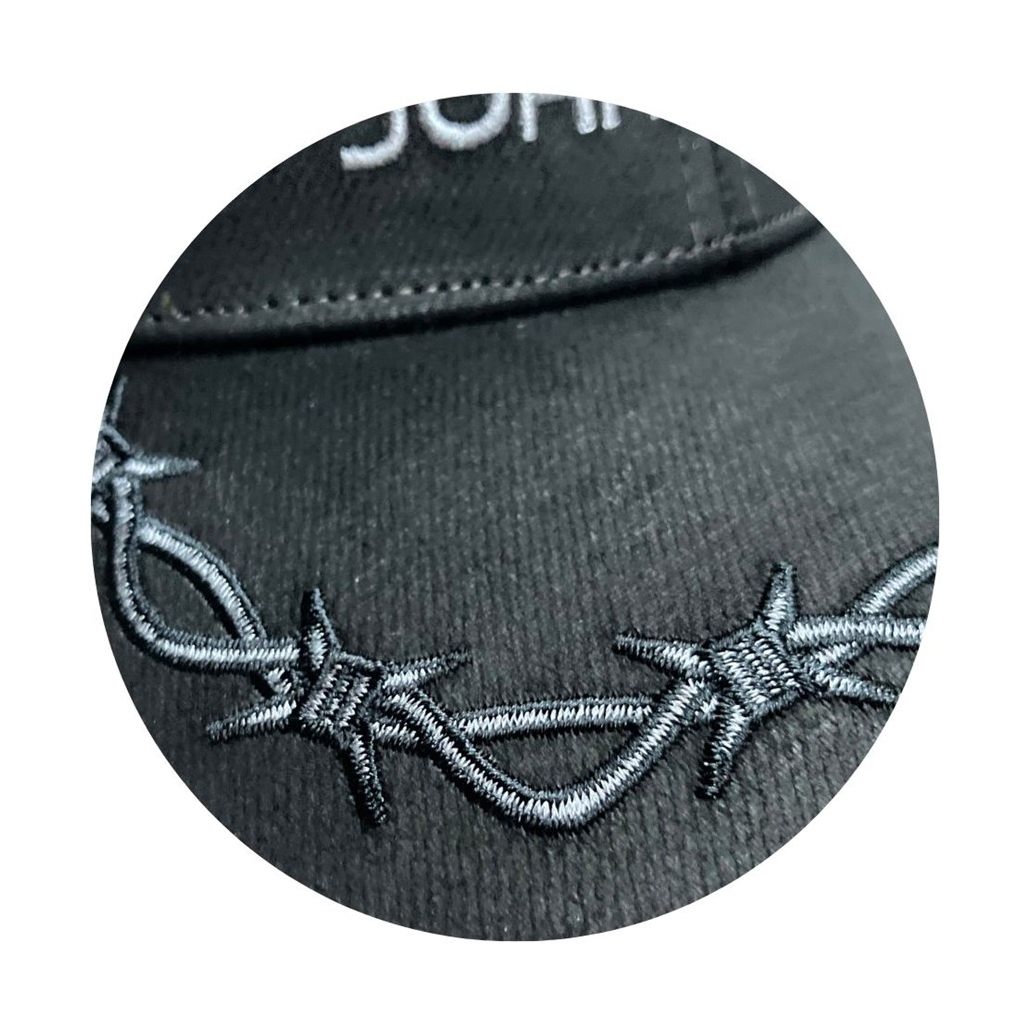 Close-up of barbed-wire embroidery on the black cap brim
