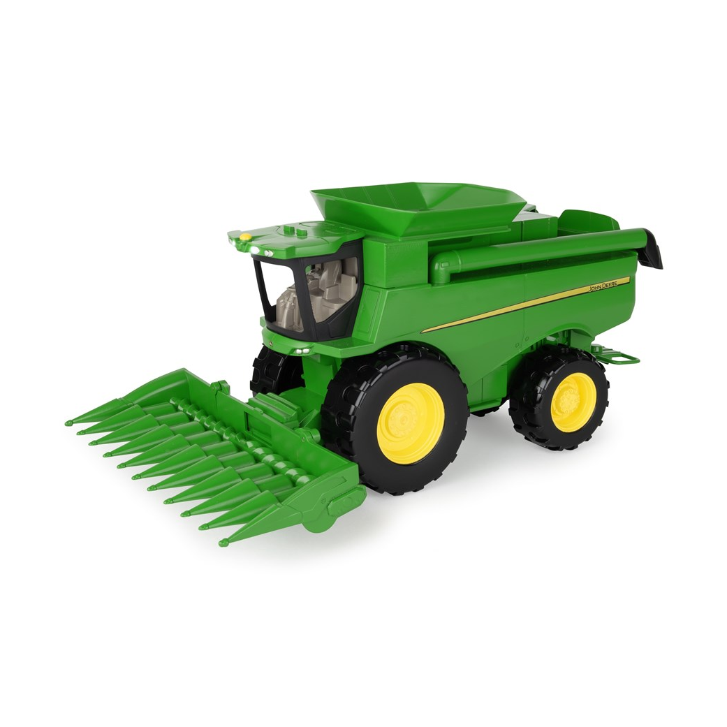 Green and yellow John Deere toy combine with corn head on a white background